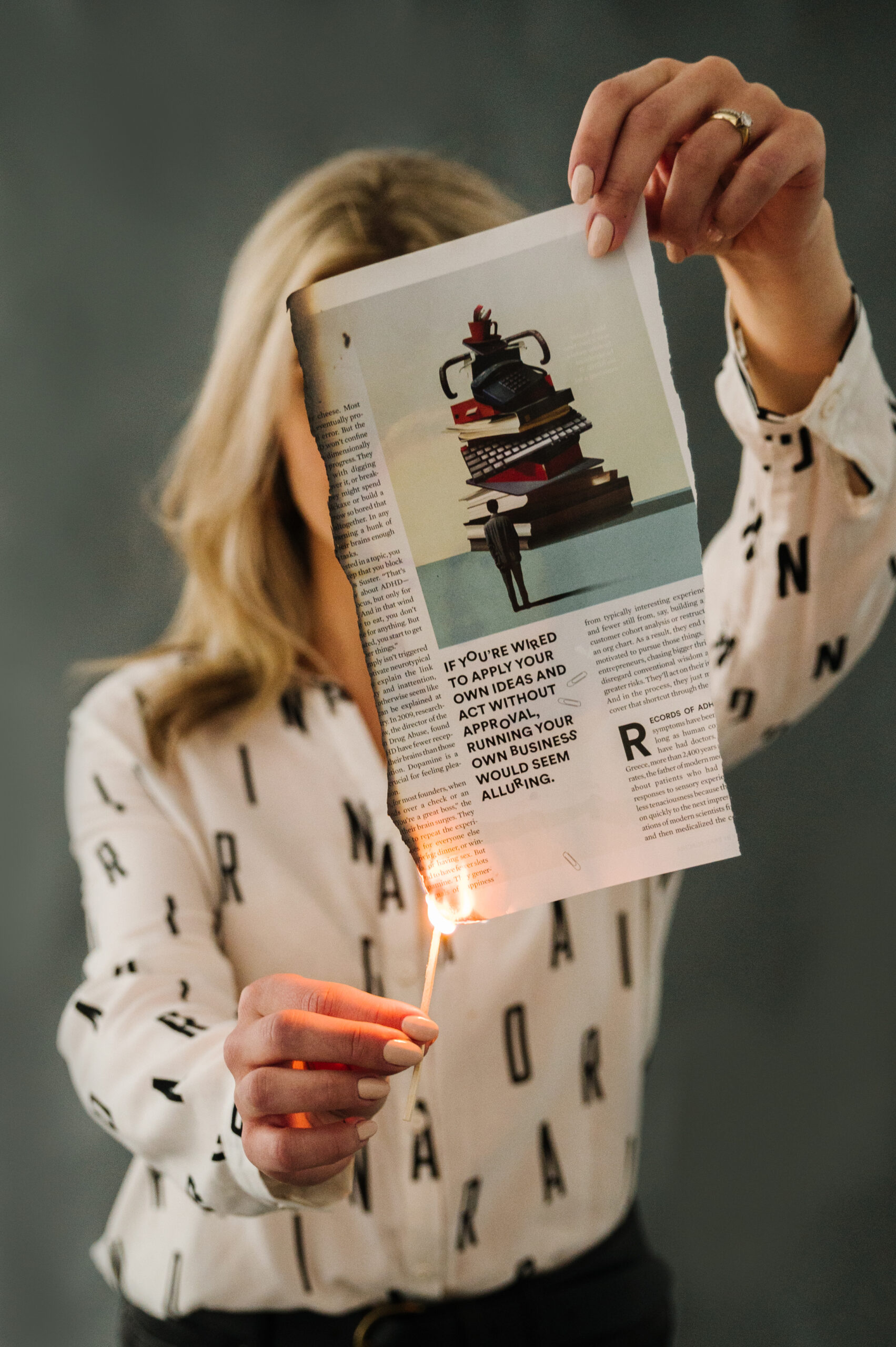 Sarah Klongerbo lighting a magazine page on fire, representing business clichés you should stop saying now