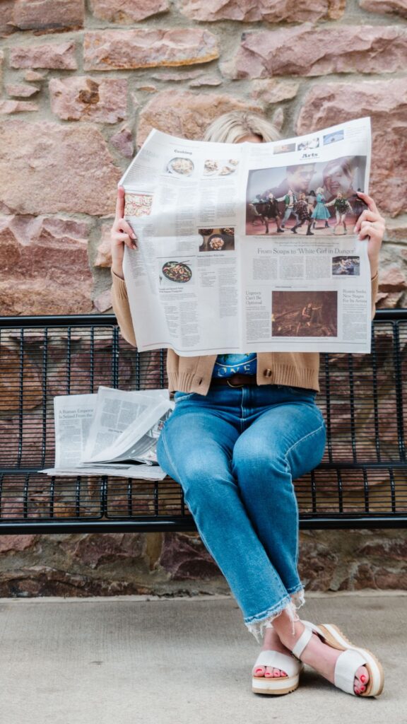 Sarah klongerbo on a bench with a newspaper